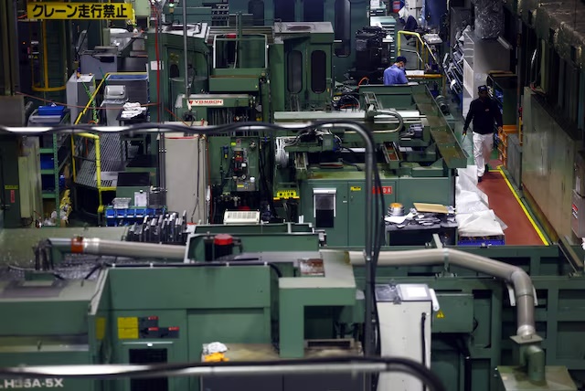 Workers walk between precision-machining machines for automotive parts inside a factory at Kyowa Industrial Co. in Takasaki, Gunma Prefecture, Japan April 11, 2025. REUTERS/Issei Kato