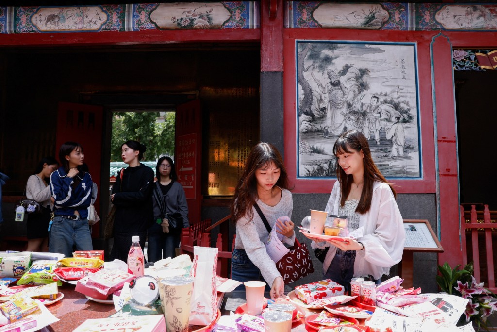 K-pop fans, mostly BTS fans, lay out snacks, group merchandise, concert seat maps and wish lists on an altar table as they pray to Yue Lao, the god of love in Chinese mythology who oversees relationships and marriage, at Taipei’s Bangka Lungshan Temple, in hopes of securing a concert ticket, in Taipei, Taiwan, May 30, 2026. (Reuters)