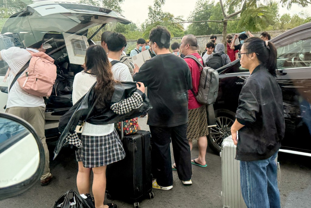 Photo by TANG CHHIN SOTHY / AFP  Workers load their luggage into waiting vehicles after walking out of a suspected scam centre compound in Sihanoukville on January 15, 2026.