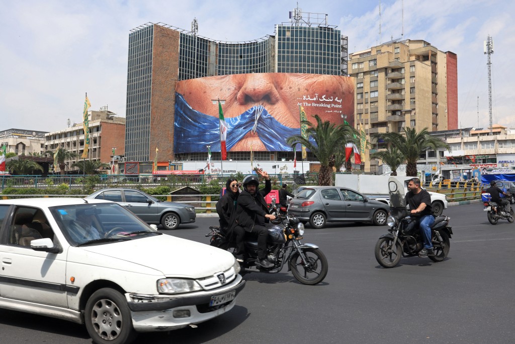 Motorists make their way past an anti-US billboard referring to President Donald Trump and the Strait of Hormuz, installed on a building at the Valiasr Square in Tehran on May 2, 2026. (AFP)