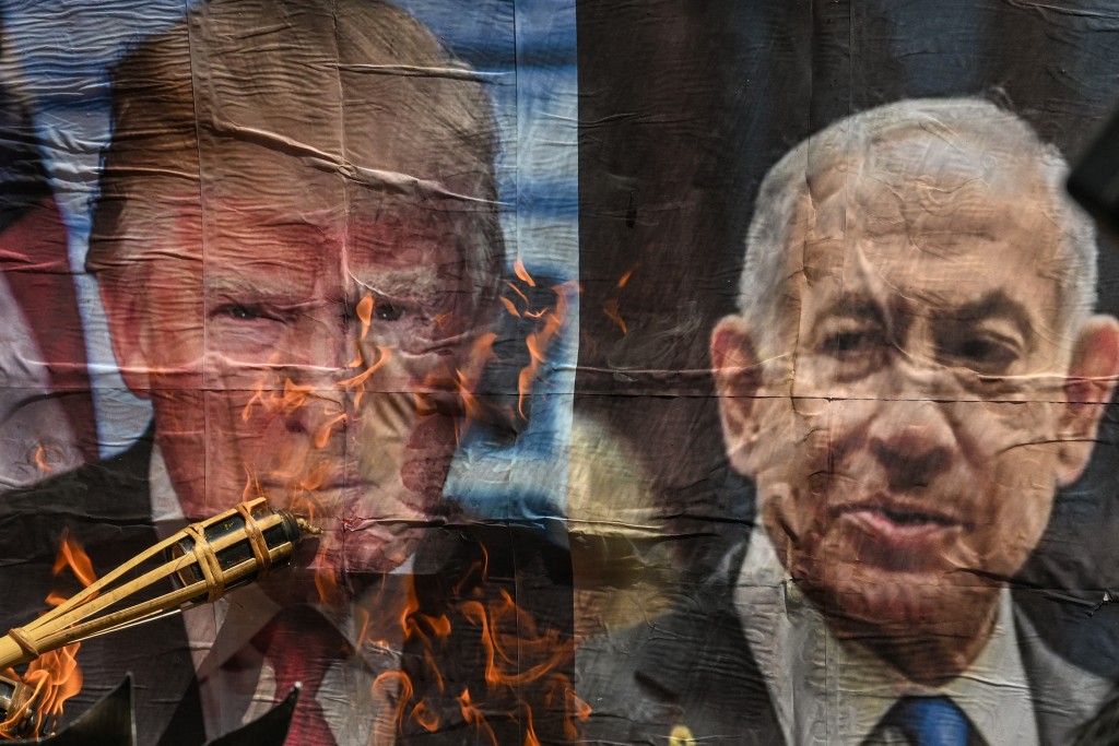 A man burns a picture of US President Donald Trump and Israeli Prime Minister Benjamin Netanyahu during a protest against the US-Israel military action in Iran, near the US Embassy in Manila on April 9, 2026. (Photo by Jam STA ROSA / AFP)