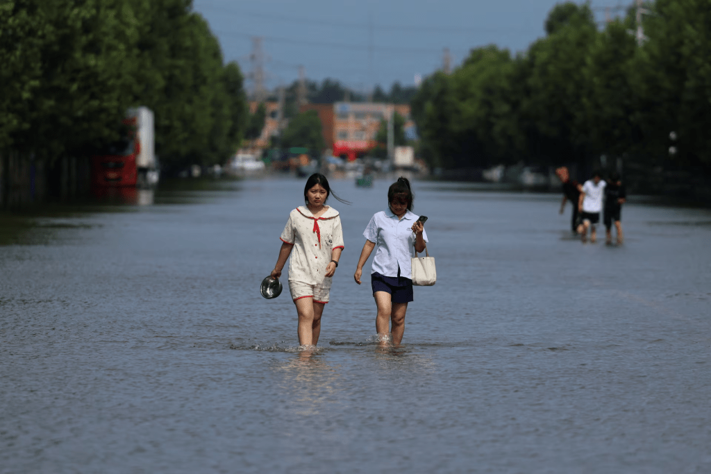 Residents wade through floodwaters, following heavy rainfall brought by remnants of Typhoon Dolphin, in Xuchang, Henan province, China August 13, 2026. REUTERS/Tingshu Wang