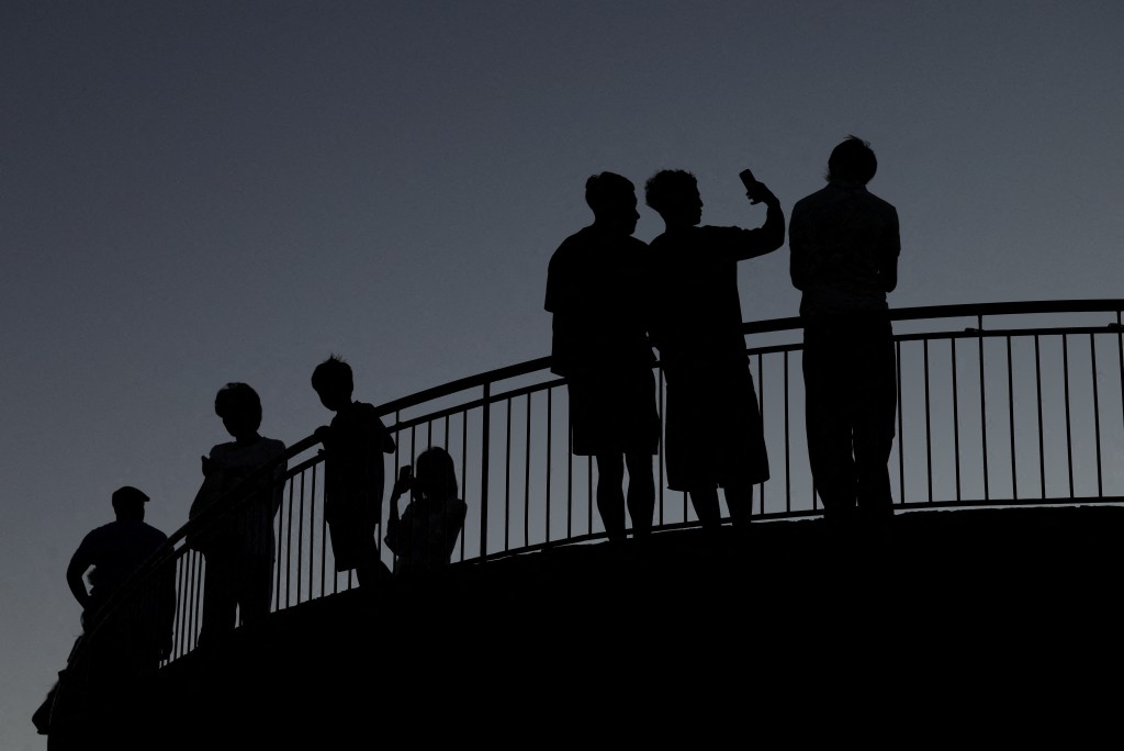 People use their mobile phones, ahead of new law banning social media for users under 16 in Australia, at dusk in Brisbane, Australia, December 8, 2025. REUTERS/Hollie Adams