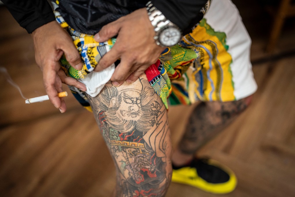 Photo by YUICHI YAMAZAKI / AFP  This photo taken on August 27, 2026 shows Tekisasu, an active yakuza gangster allied to a major clan, showing his tattoos on his leg at a barbershop in Tokyo.
