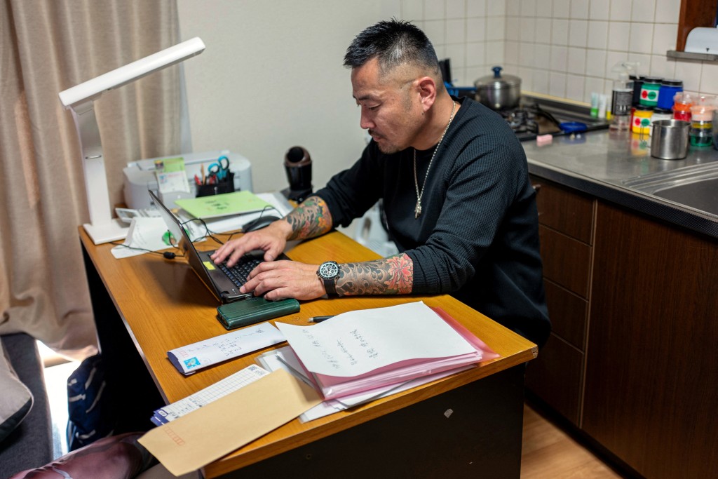Photo by KAZUHIRO NOGI / AFP  This photo taken on November 7, 2025 shows former gangster Yoshiro Nishino handling paperwork at his group home for ex-offenders in Chiba Prefecture.