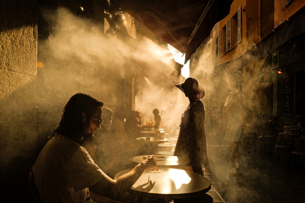 People stand in front of a coffe shop during a heatwave in the French Riviera city of Nice. (AFP)