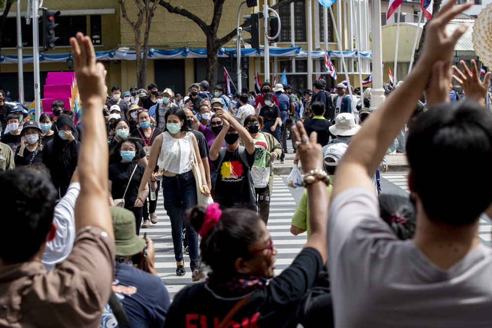 Pro-democracy activists raise three-fingers, symbol of resistance salute, welcoming others ahead of a protest at Democracy Monument in Bangkok, Thailand, Sunday.