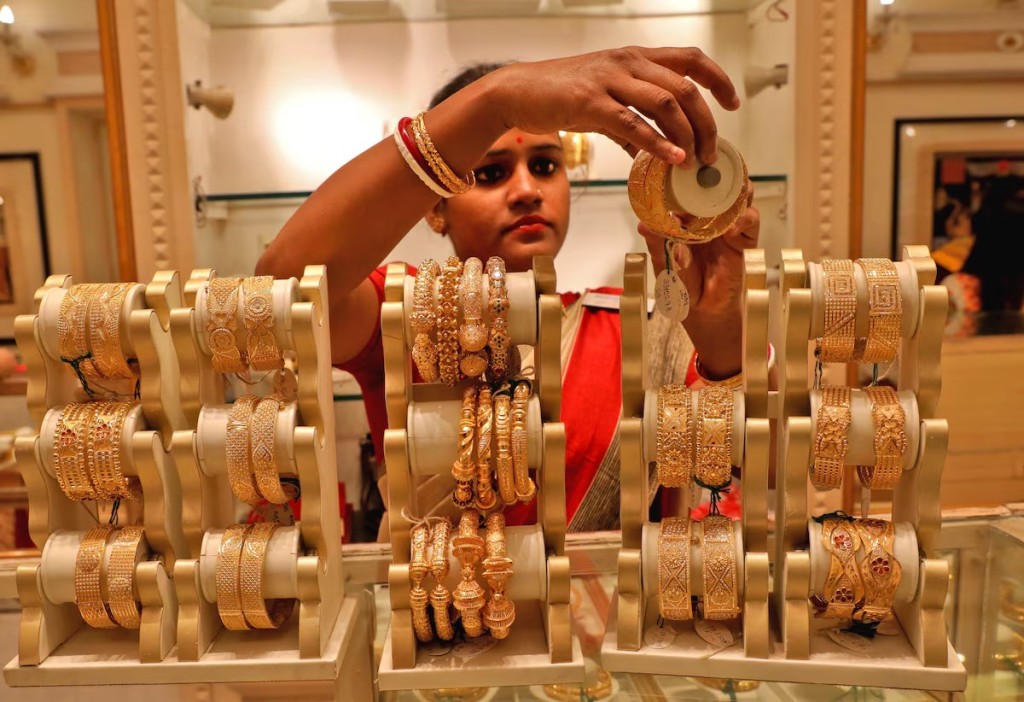 A saleswoman shows gold bangles to a customer at a jewellery showroom on the occasion of Akshaya Tritiya, a major gold buying festival, in Kolkata, India, May 3, 2022. REUTERS