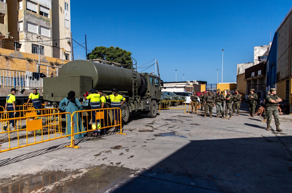 Photo by ANTONIO SEMPERE / AFP Spanish soldiers supervise a water distribution at a settlement for migrants in the Spanish North African enclave of Ceuta on August 7, 2026, following a mass influx of migrants from Morocco in recent days.