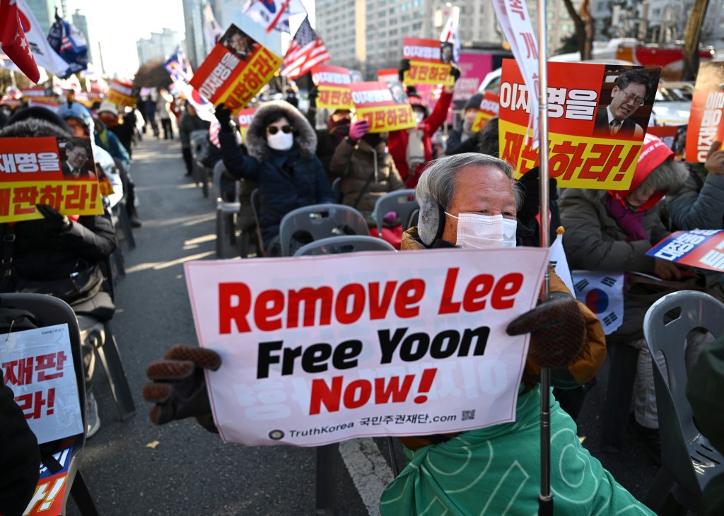Supporters of South Korea's ousted president Yoon Suk Yeol hold a placard reading "Remove Lee, Free Yoon now!" during a rally marking the first anniversary of Yoon's declaration of martial law, in front of the National Assembly in Seoul on December 3, 2025. (Photo by Jung Yeon-je / AFP)