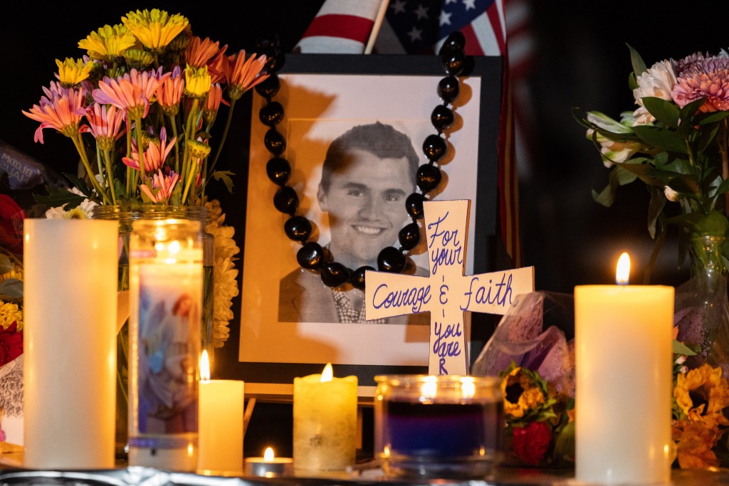 Candles and flowers are seen near a portrait of right-wing activist Charlie Kirk at a makeshift memorial during a candlelight vigil at Memorial Park in Provo, Utah, on September 12, 2025, after he was shot during a public event at Utah Valley University. (Photo by Melissa MAJCHRZAK / AFP)