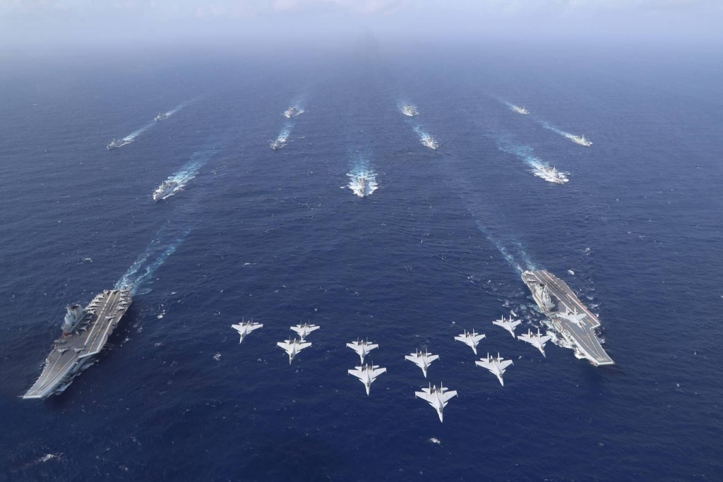A J-15 formation overflying Chinese carriers Shandong (left) and Liaoning, followed by their escorts, in the South China Sea. (File Photo)