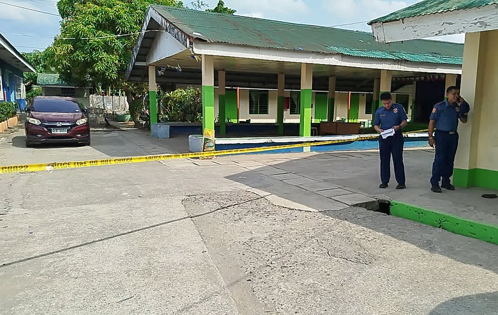 Philippine police investigators walk in front of a high school in Leyte province where a rare mass shooting incident took place Monday © Noel Sianosa / AFP