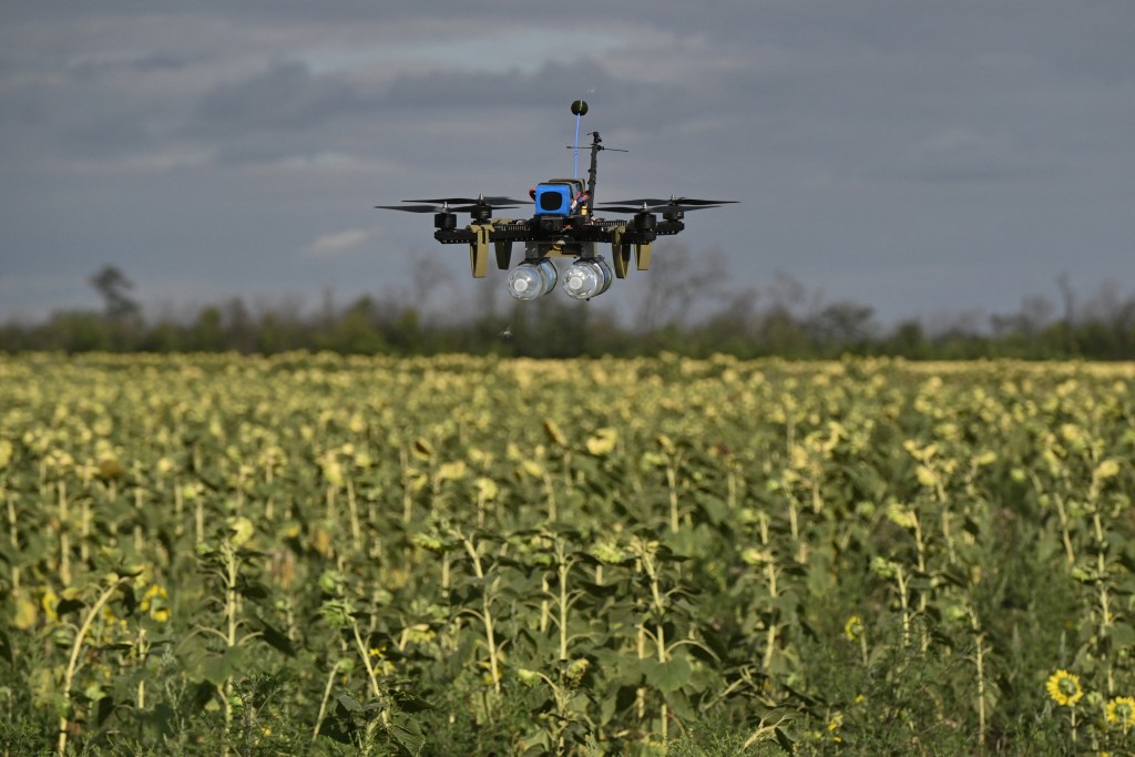 Photo by GENYA SAVILOV / AFP  This photograph shows a FPV drone of the Reconnaissance Company "Only Wars" of the Ukrainian 3rd Army Corps caring bottles of water which imitate a combat load during a training flight over a sunflower field in an undisclosed location, in eastern Ukraine on August 12, 2025, amid the Russian invasion of Ukraine.