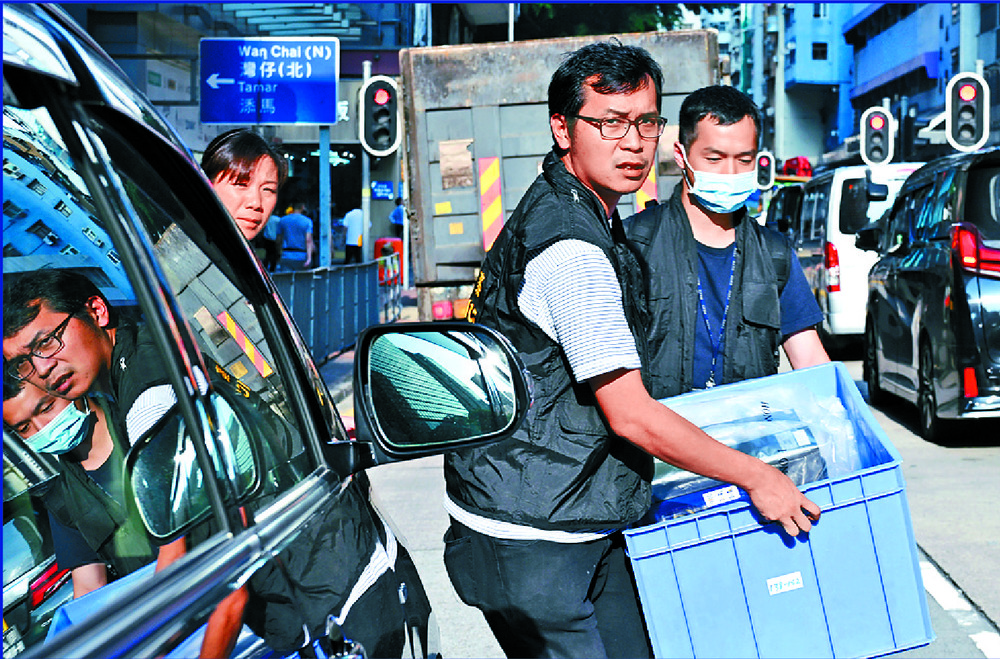 Customs officers seize evidence from Physical Fitness's Causeway Bay branch as people check in at the Wan Chai gym, where a customer later works out at a machine. SING TAO