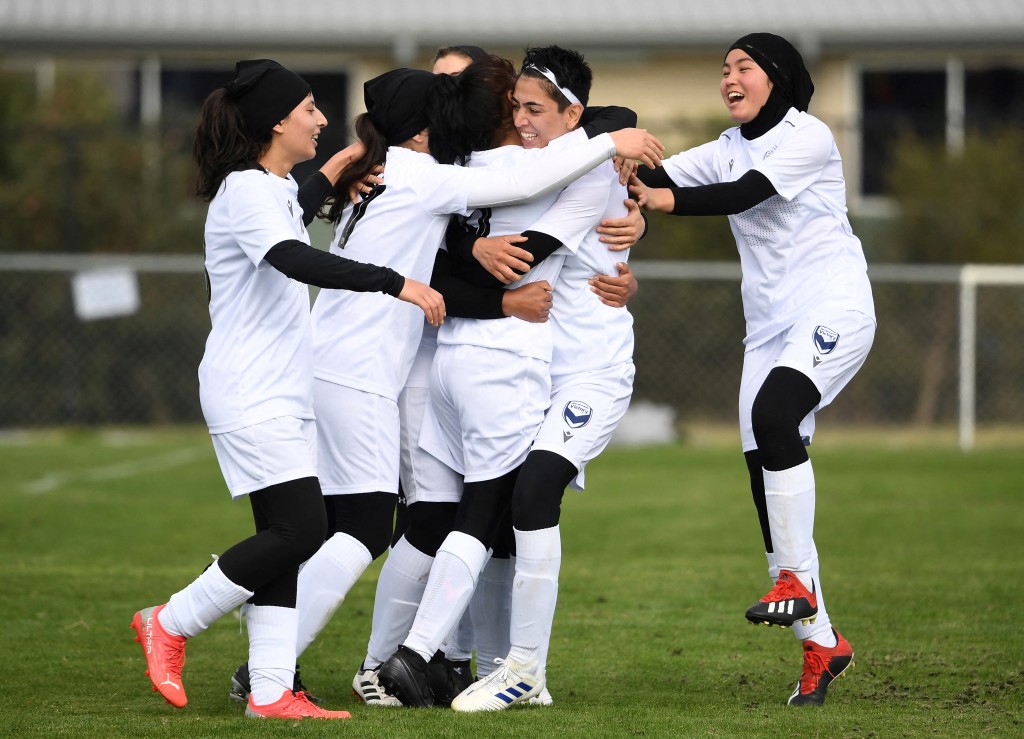Photo by WILLIAM WEST / AFP. Members of the Afghanistan's national women's football team playing under the Melbourne Victory Afghan women’s team banner celebrate a goal in their first match in a local league against ETA Buffalo SC in Melbourne on April 24, 2022.