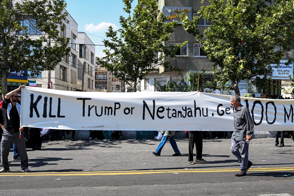 Photo by WAKIL KOHSAR / AFP Mourners hold up a large banner urging a reward for revenge against US President Donald Trump and Israeli Prime Minister Benjamin Netanyahu during a funerary procession for Iran's slain supreme leader Ali Khamenei and his family members near Azadi Square in Tehran on July 6, 2026.
