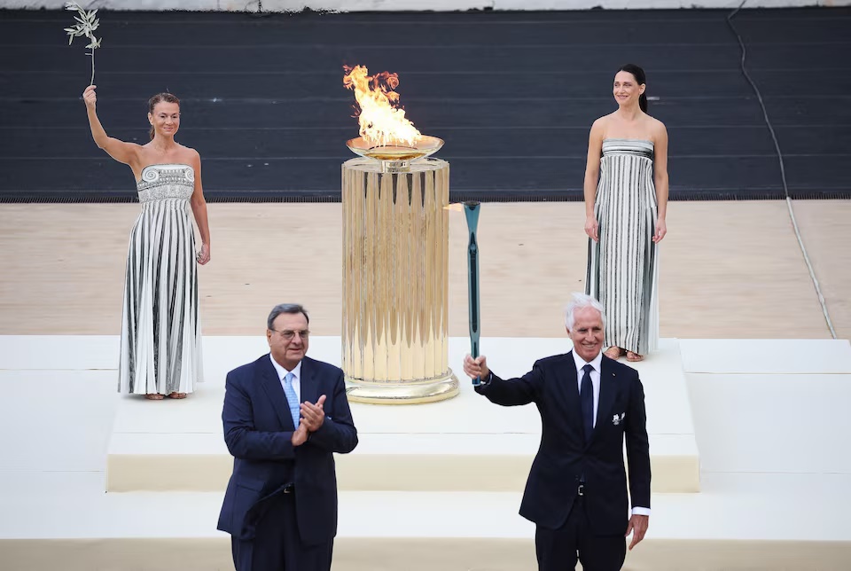 Winter Olympics - 2026 Milano-Cortina Winter Olympic Flame handover ceremony - Panathenaic Stadium, Athens, Greece - December 4, 2025 President of the Milano Cortina 2026 Organizing Committee, Giovanni Malago holds the Olympic flame during the ceremony as President of the Hellenic Olympic Committee, Isidoros Kouvelos applauds REUTERS/Louisa Gouliamaki