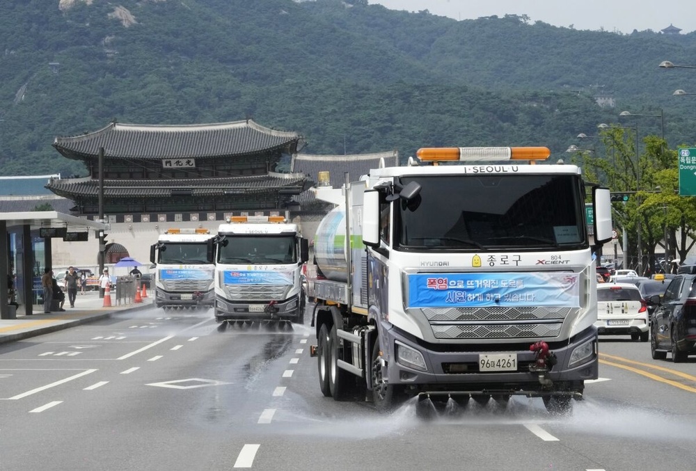 Sprinkler trucks spray water on a road to cool the heat in Seoul on Aug. 2.Photographer: Ahn Young-joon/AP Photo Sprinkler trucks spray water on a road to cool the heat in Seoul on Aug. 2.Photographer: Ahn Young-joon/AP Photo