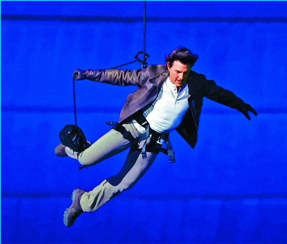 Tom Cruise abseils from the roof of the Stade de France to receive the Olympic flag from gymnastics champion Simone Biles and Los Angeles mayor Karen Bass before riding off with it on his motorcycle. REUTERS