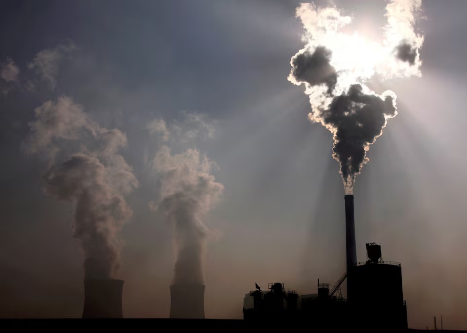  A coal-burning power plant can be seen behind a factory in the city of Baotou, in China's Inner Mongolia Autonomous Region, October 31, 2010. REUTERS/David Gray/File Photo 