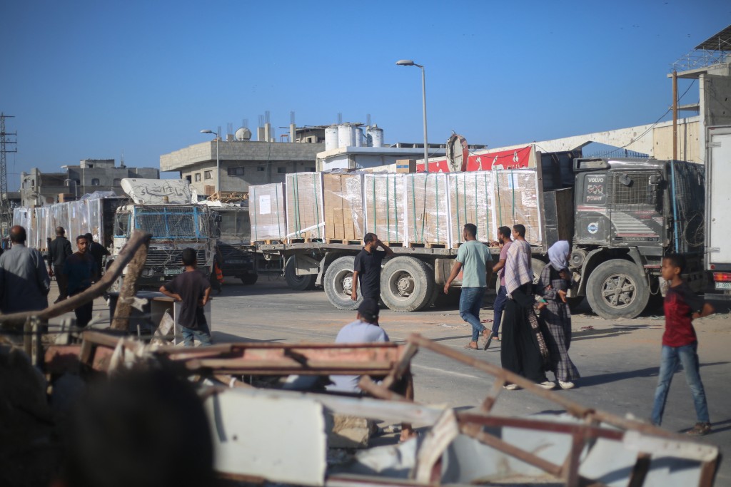 Photo by EYAD BABA / AFP.  Displaced Palestinians gather around a truck to receive aid supplies that entered Gaza in the morning at the Nuseirat refugee camp in the central Gaza Strip, on October 20, 2025.