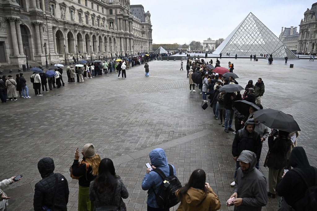 People queue in the Louvre pyramid courtyard moments before the announcement the museum will remain closed for a second day running after thieves stole crown jewels from the museum in Paris a day earlier, in Paris on October 20, 2025. (AFP)