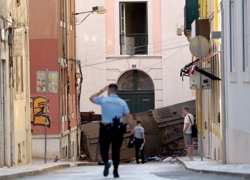 Police walk toward the roof of the destroyed Gloria funicular one day after the accident. (AFP)