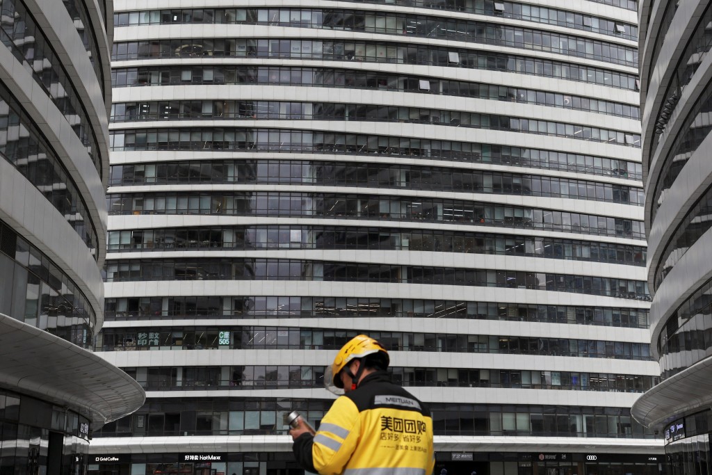 A Meituan delivery worker walks among office towers in Beijing, China March 27, 2025. REUTERS/Florence Lo