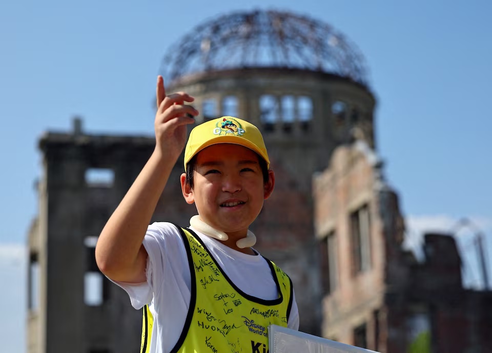 Shun Sasaki, 12, an elementary school student in Hiroshima, guides foreign visitors in English as a volunteer guide in front of the Atomic Bomb Dome in Hiroshima, western Japan July 15, 2025. REUTERS/Issei Kato