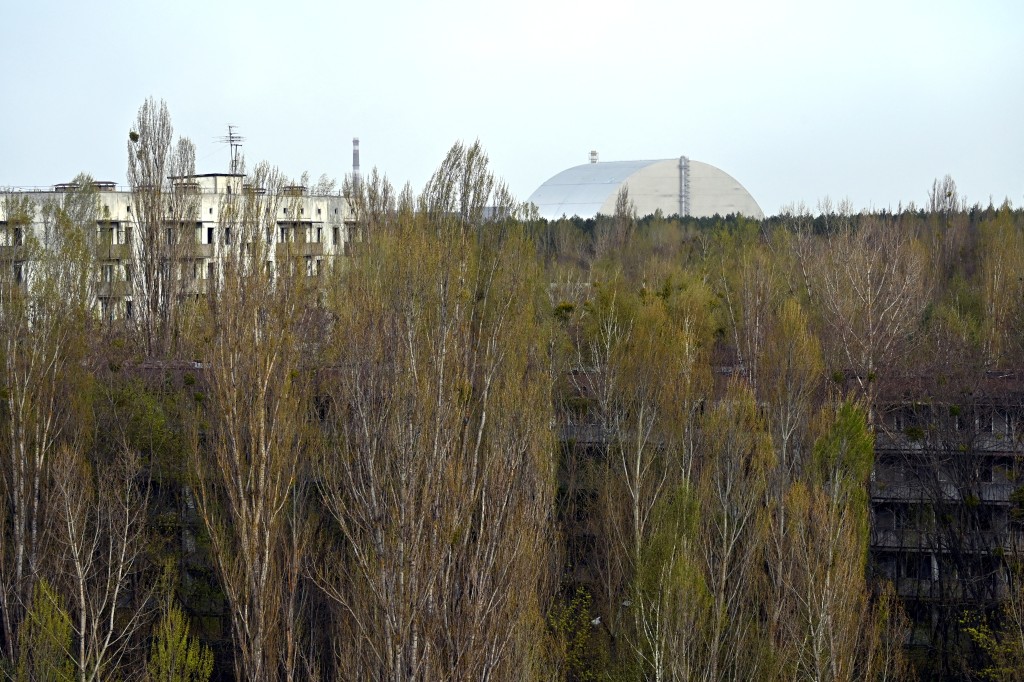 Photo by SERGEI SUPINSKY / AFP  The New Safe Confinement (NSC), covering the destroyed fourth reactor at the Chernobyl Nuclear Power Plant is seen from the ghost city of Pripyat on April 23, 2026.