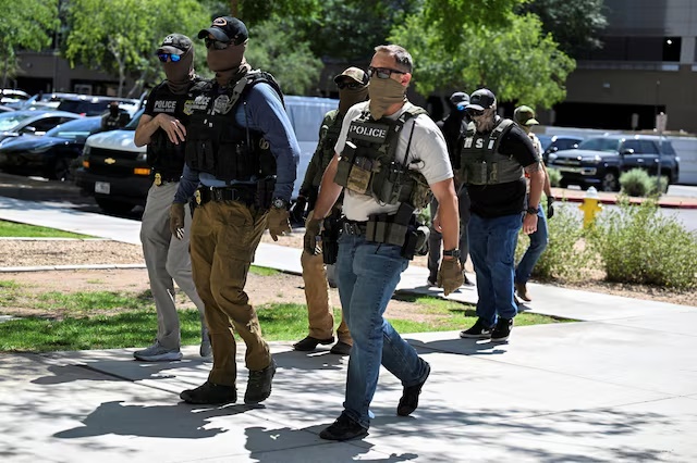 Masked law enforcement officers, including HSI and ICE agents, walk into an immigration court in Phoenix, Arizona, U.S., May 21, 2025. REUTERS/Caitlin O'Hara/File Photo