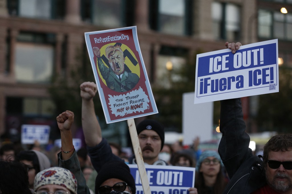 People hold signs while protesting the arrival of the Texas National Guard and US Immigration and Customs Enforcement agents in downtown Chicago, Illinois, on October 8, 2025. Chicago, the third-largest in the country, has become the latest flashpoint in a crackdown by US Immigration and Customs Enforcement (ICE) agents that has sparked allegations of rights abuses and myriad lawsuits. (Photo by OCTAVIO JONES / AFP)