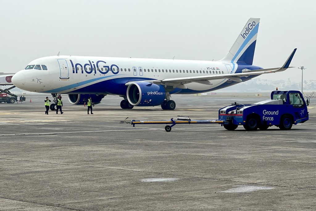 Ground staff walk past an Indigo airlines aircraft taxiing in the apron at the Netaji Subhash Chandra Bose International airport in Kolkata. (AFP)