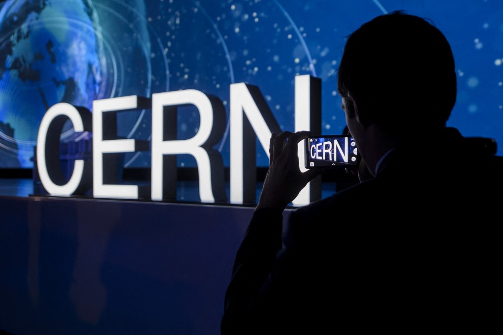 Photo by FABRICE COFFRINI / AFP  A guest takes a picture of the European Organisation for Nuclear Research (CERN) logo during an official ceremony marking the 60th anniversary of CERN in Meyrin near Geneva on September 29, 2014.
