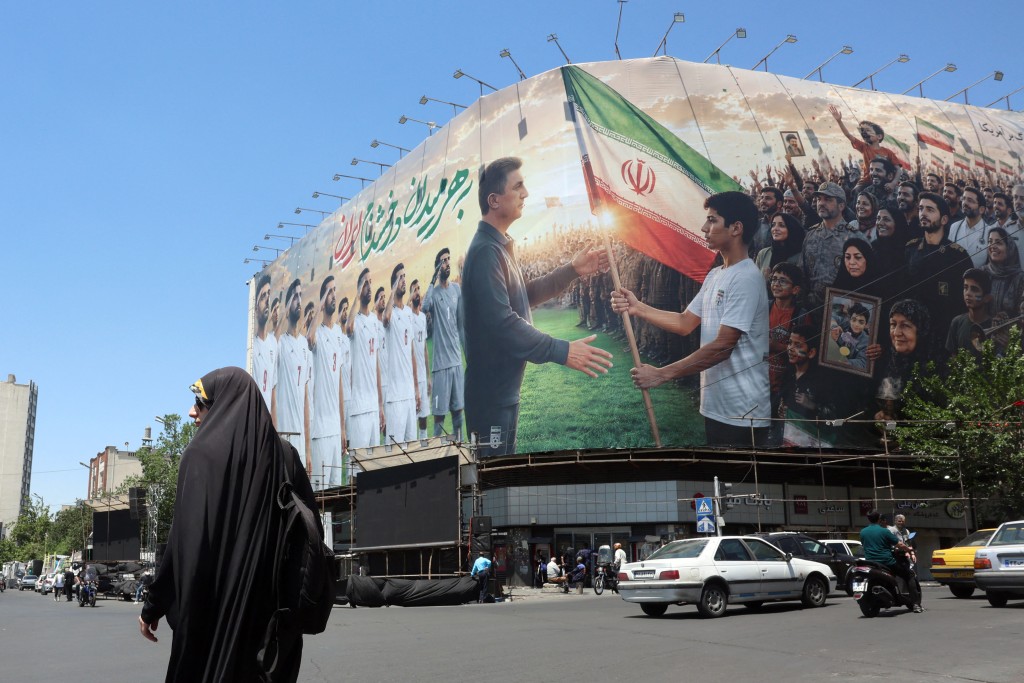 An Iranian woman walks past a huge billboard supporting Iran’s national football team in the upcoming 2026 World Cup, installed on a building at Enghelab Square in Tehran on May 18, 2026. (AFP)