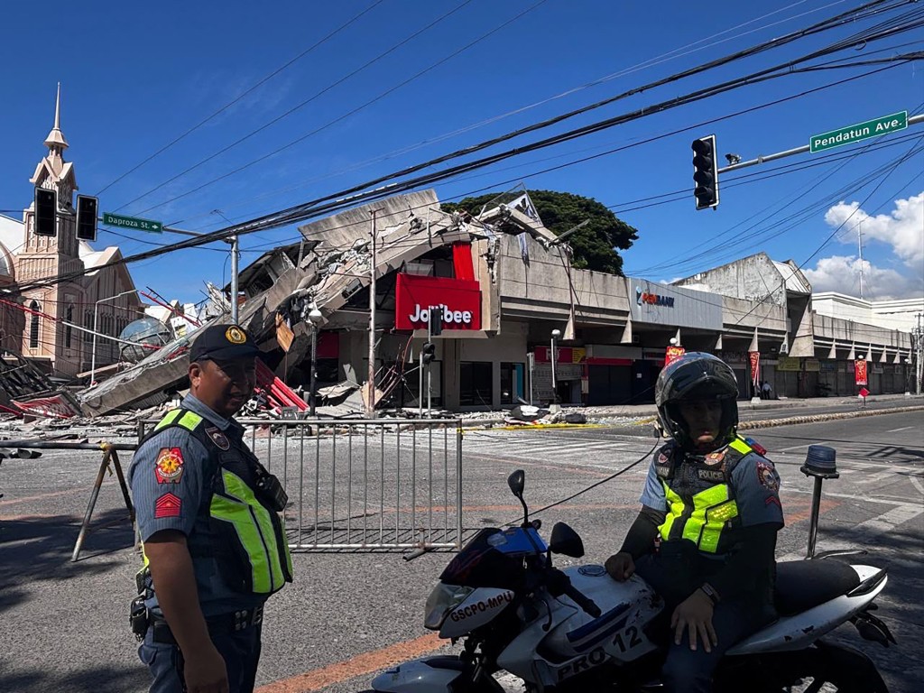 Police gather in front of a collapsed Jollibee fast food restaurant after an 7.8 magnitude earthquake in General Santos City on June 8, 2026. (AFP)