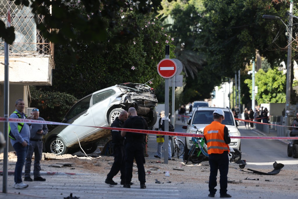Israeli police and first responders gather at the site of an Iranian missile strike in the center of the Israeli coastal city of Tel Aviv, on March 8, 2026. (AFP)