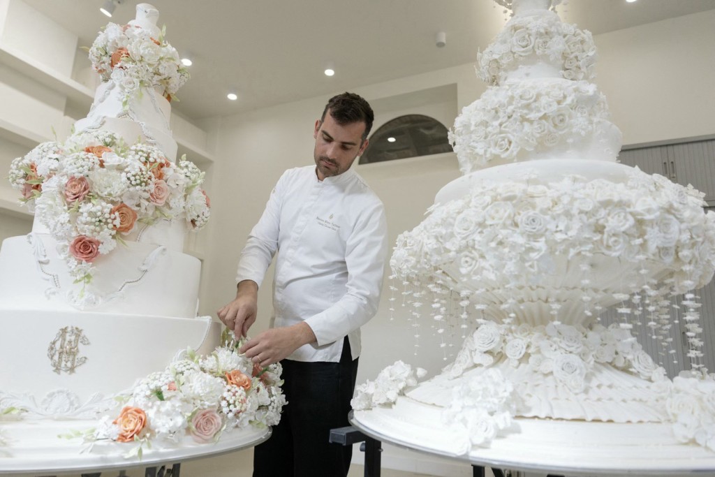 THOMAS SAMSON / AFP Photo by THOMAS SAMSON / AFP French pastry chef Bastien Blanc-Tailleur decorates a wedding cake at his studio in Saint-Remy-les-Chevreuse, southwestern Paris on April 10, 2026.