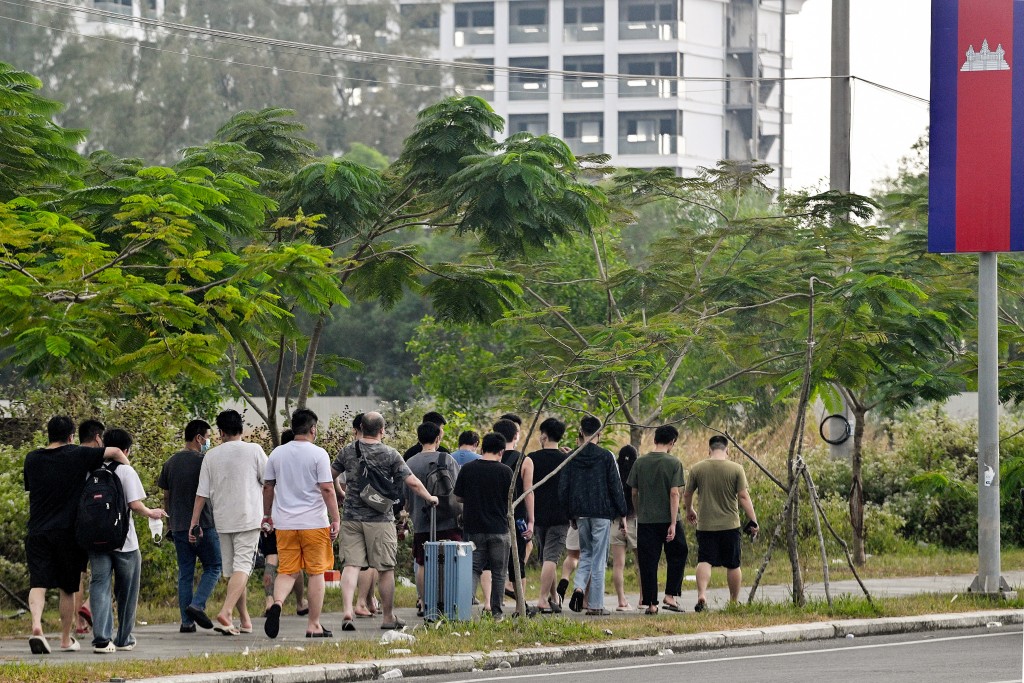 Photo by TANG CHHIN SOTHY / AFP  Workers walk out of a suspected scam centre compound in Sihanoukville on January 15, 2026.