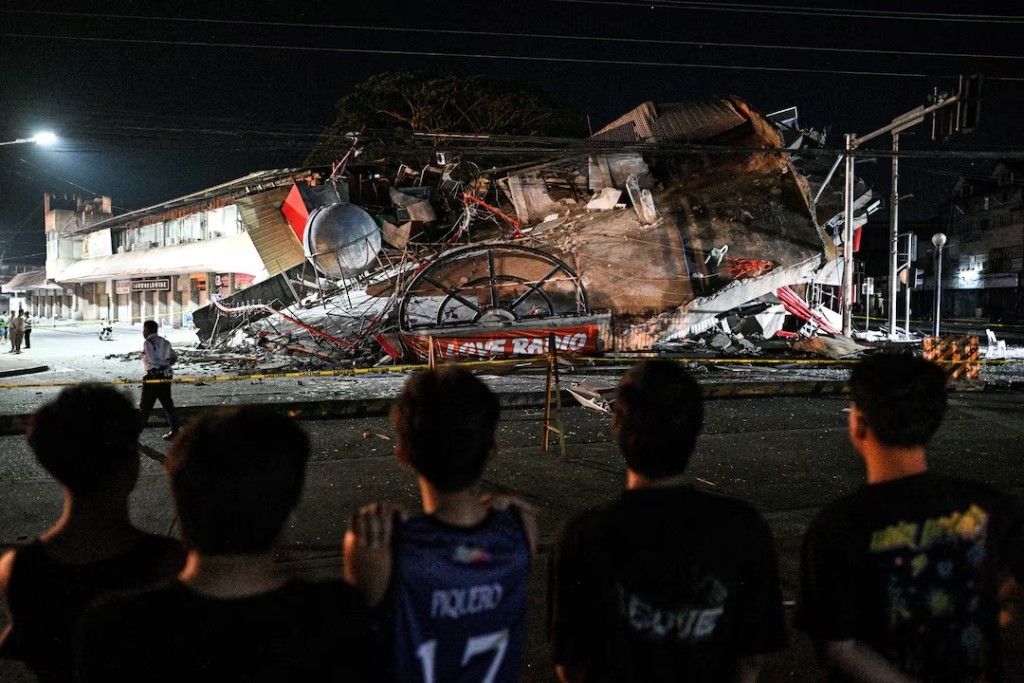 People look at a collapsed building following the magnitude 7.8 quake in General Santos, southern Philippines, June 8. REUTERS/Noel Celis 