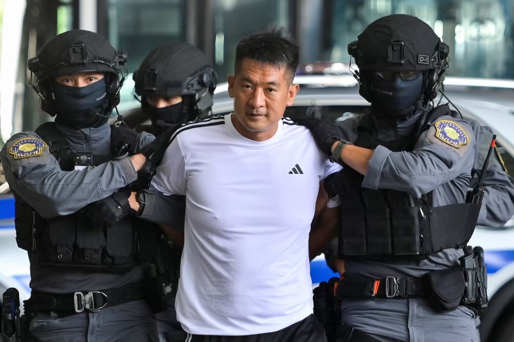 She Zhijiang, 43, a Chinese national gambling kingpin who was arrested by Thai police in August 2022 on an international warrant and an Interpol red notice requested by Beijing of having run illegal online gambling operations, is escorted by police ahead of being extradited to China, at Bangkok Suvarnabhumi Airport, in Samut Prakan, Thailand, November 12, 2025. REUTERS/Thanaphon Wuttison