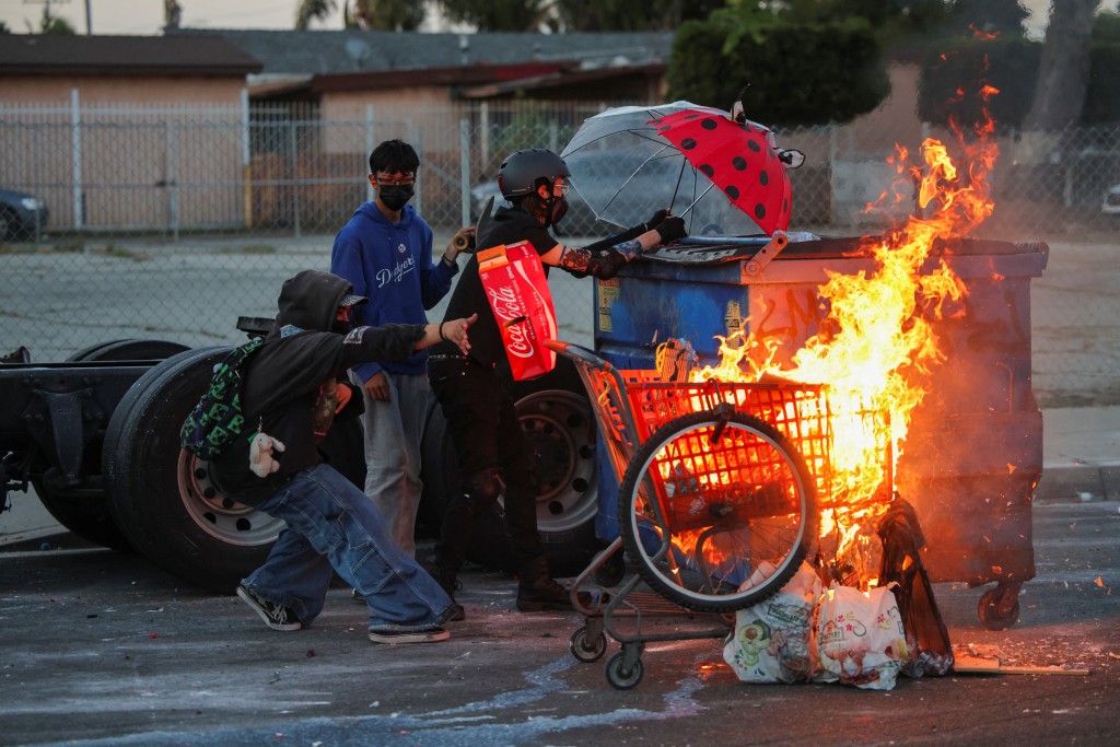 Protesters stand next to a burning shopping cart during a standoff between police and protesters following multiple detentions by Immigration and Customs Enforcement (ICE), in the Los Angeles County city of Paramount, California, U.S., June 7, 2025. (Reuters)