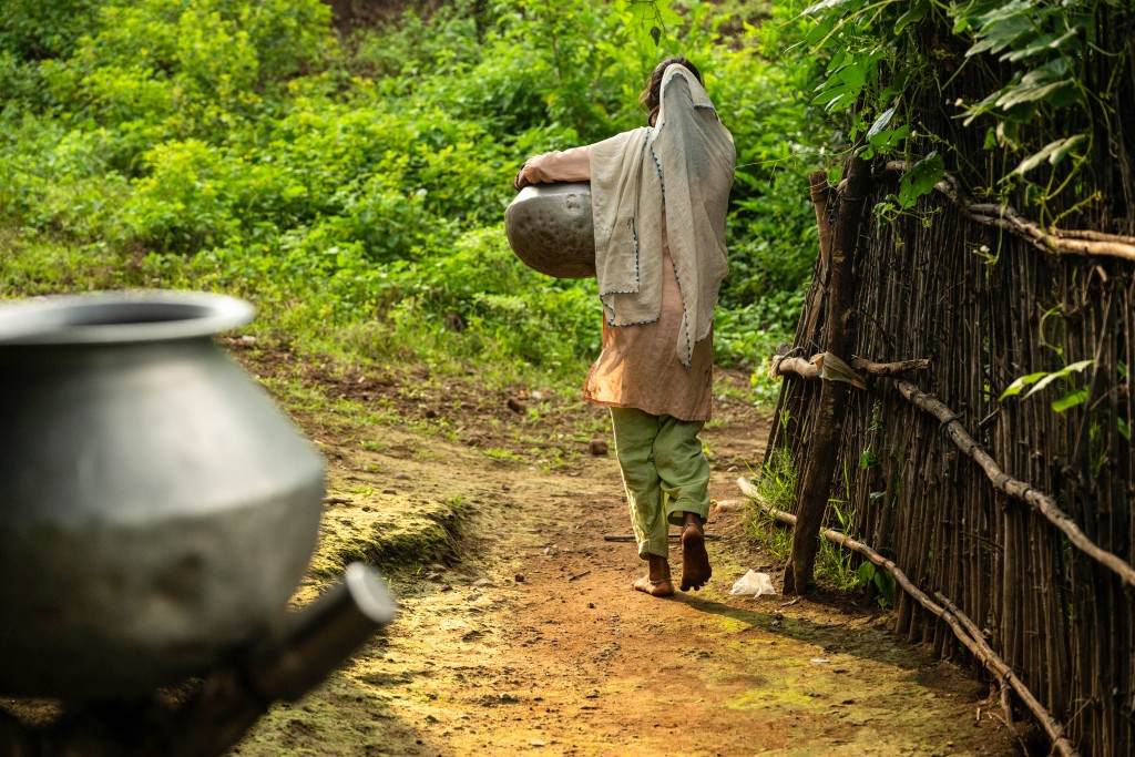 Photo by SHEFALI RAFIQ / AFP  In this photograph taken on September 23, 2025, Sangita Santosh, who dropped out of school to manage household chores, carries a pot to fetch water from a spring at Khaparmal village in the drought-prone district of Nandurbar.