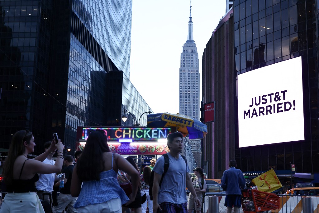 Photo by CHARLY TRIBALLEAU / AFP  The Empire State Building is seen in the distance as people take photos of a giant screen showing the message "JUST&T MARRIED!"