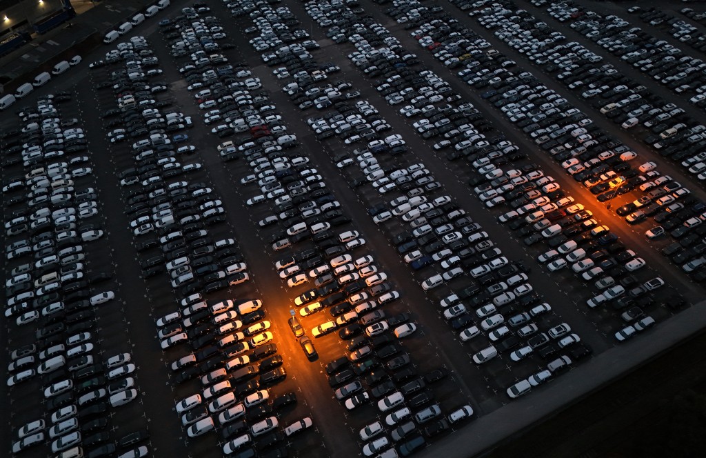 An aerial view taken on August 4, 2025 in Essen, western Germany, shows cars of various brands that are parked ready for sale and export at a car logistics terminal. Europe's auto industry is relieved that the EU-US trade deal reduces short-term uncertainty but many, particularly in the struggling German sector, remain deeply worried about the long-term impact. (Photo by Ina FASSBENDER / AFP)