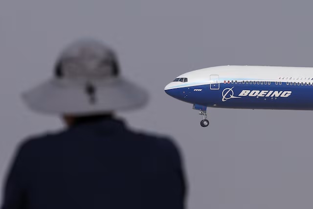 A Boeing 777X aircraft performs a flypast in front of an attendee at the Dubai Airshow in Dubai, United Arab Emirates, November 17, 2025. REUTERS/Amr Alfiky