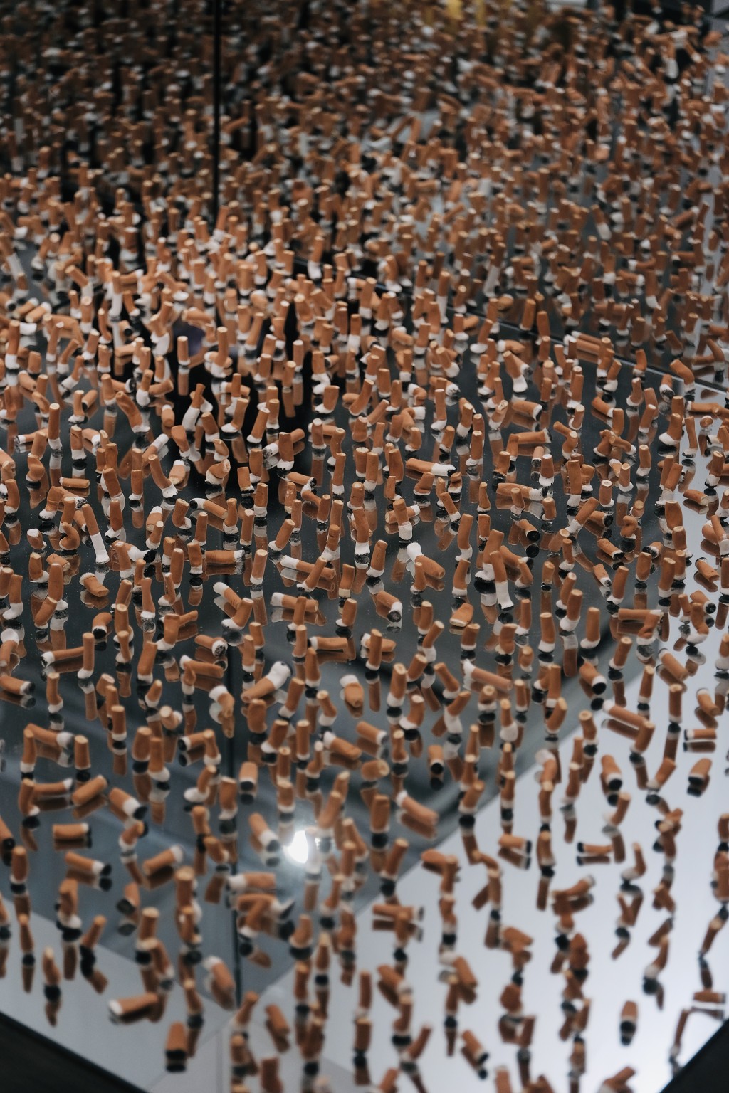 More than 800 hand-shaped ceramic cigarette butts capture traces of exhausted goodbyes and suspended moments where private emotion quietly lingers in public space.