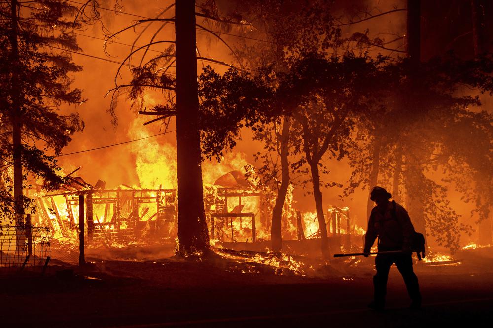 A firefighter passes a burning home as the Dixie Fire flares in Plumas County, Calif., Saturday, July 24, 2021. The fire destroyed multiple residences as it tore through the Indian Falls community. A firefighter passes a burning home as the Dixie Fire flares in Plumas County, Calif., Saturday, July 24, 2021. The fire destroyed multiple residences as it tore through the Indian Falls community.