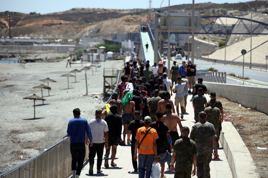 A group of migrants approach the border post to make their way back to Morocco, escorted by Spanish infantry soldiers, in the Spain's north African enclave of Ceuta, on August 2, 2026. (AFP)